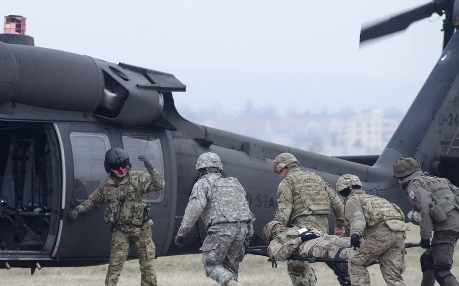 A UH-60 Blackhawk helicopter crew chief, left,  from the 214th Aviation Regiment waves on U.S. and Austrian soldiers carrying a stretcher-borne casualty during an international combat lifesaver course on Thursday, Feb. 2, 2017, at Clay Kaserne in Wiesbaden, Germany.