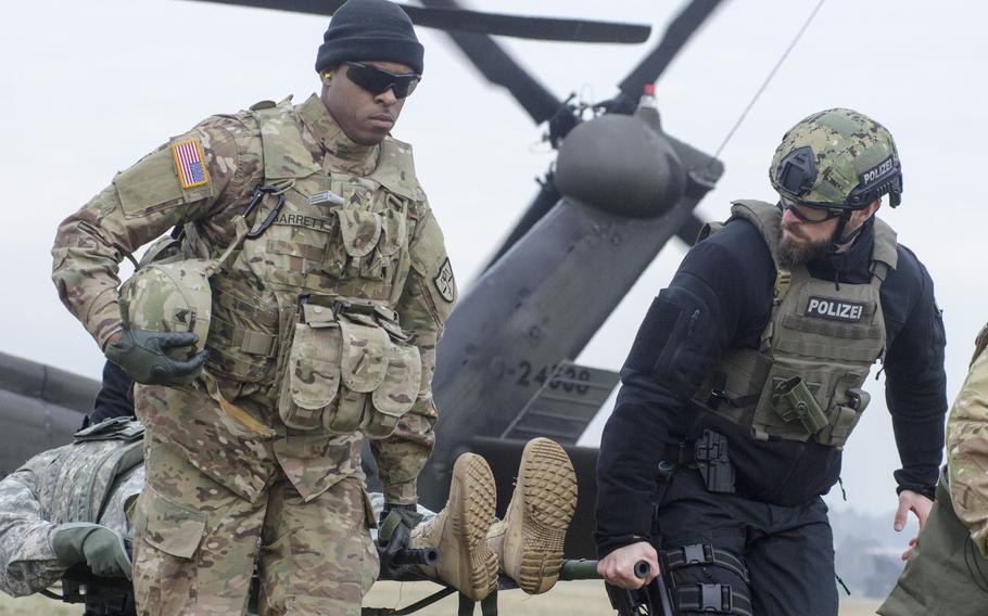 A U.S. soldier and German polizei officer carry a stretcher-borne casualty off of a UH-60 Blackhawk helicopter during an international combat lifesaver course on Thursday, Feb. 2, 2017, at Clay Kaserne in Wiesbaden, Germany.