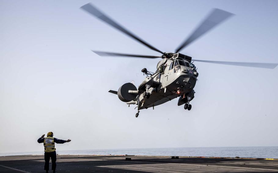 A flight deck crew member onboard the British helicopter carrier HMS Ocean directs a Sea King MK7 airborne surveillance and control helicopter taking off during exercise Unified Trident in the Persian Gulf, Jan. 31, 2016.  