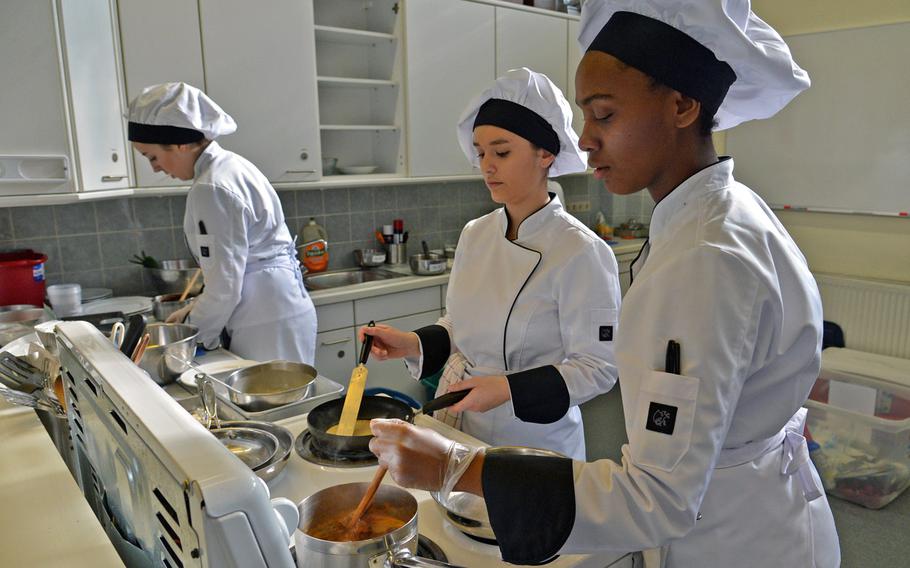 Wiesbaden's Majesty Henry, right, stirs a sauce as Myrah Hernandez cooks a crepe and Jamie Caskey prepares a dish at the DODEA-Europe Culinary Arts Championships in Kaiserslautern, Germany, Wednesday, Feb. 15, 2017.