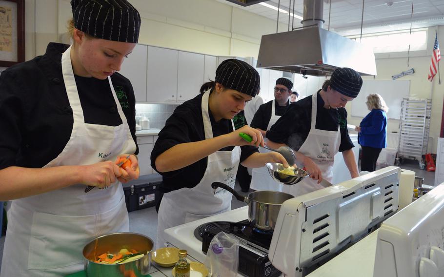 Naples' Kaethe Rose, Madison Doran and Nicholas Sherer, from left, prepare their three-course menu at the DODEA-Europe Culinary Arts Championships in Kaiserslautern, Germany, Wednesday, Feb. 15, 2017. Naples alternate Harrison Quinton, in the background, keeps time.