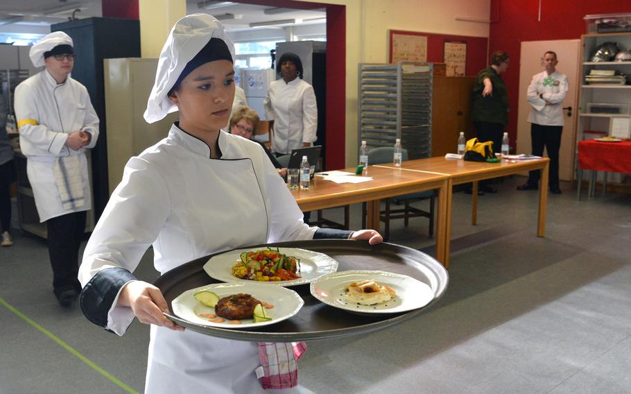Wiesbaden's Myrah Hernandez carries her team's dishes to the judging room  at the DODEA-Europe Culinary Arts Championships in Kaiserslautern, Germany, Wednesday, Feb. 15, 2017.They cooked crab cakes, honey sriracha orange chicken and Caribbean crepe at the competition.