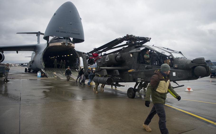 A load crew pushes an AH-64 Apache clear of a C-5 Galaxy at Ramstein Air Base, Germany, on Wednesday, Feb. 22, 2017.