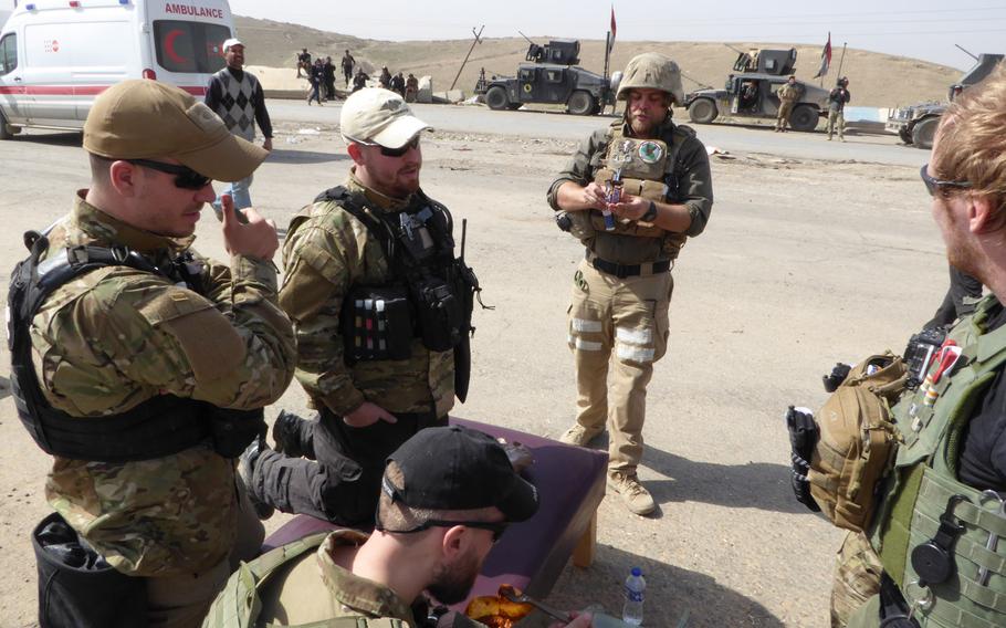 Volunteer medics working with the nonprofit Academy of Emergency Medicine take a break Tuesday, Feb. 28, 2017, while waiting for possible casualties from an Iraqi army offensive to retake a nearby Mosul neighborhood from the Islamic State group. Standing, from left: Matej Karlak, Oliver Valentovic and Derek Coleman.