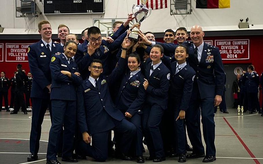 SHAPE's drill team hoists the overall team champion trophy in a group photo with Maj. Gen. Timothy Zadalis, U.S. Air Forces in Europe and Africa vice commander, right, during the DODEA-Europe JROTC drill team championships in Kaiserslautern, Germany, on Saturday, March 4, 2017. SHAPE also won seven other team and individual awards during the competition.