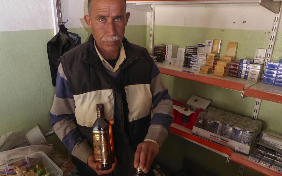 Yazidi Khiri Elias sells alcohol from a small shop in Bashiqa, Iraq, Monday, March 6, 2017. The village near Mosul was liberated in early November. Some families and businesses have begun returning, despite a great deal of destruction caused by fighting to oust Islamic State fighters who had held it since 2014.