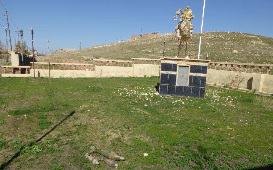 Mortars lie in the grass in front of a destroyed statue of a Yezidi hero in Bahzani, Iraq, Monday, March 6, 2017.