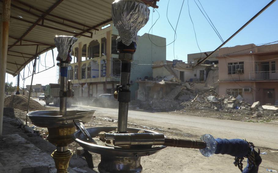 Hookah pipes stand in front of Bassam Makhmoud's shop, across from a destroyed house in Bakhzani, Iraq, Monday, March 6, 2017. Many buildings in the village were destroyed in the fight to liberate the area from the Islamic State group, which held it for roughly 2 1/2 years until it was liberated in November.