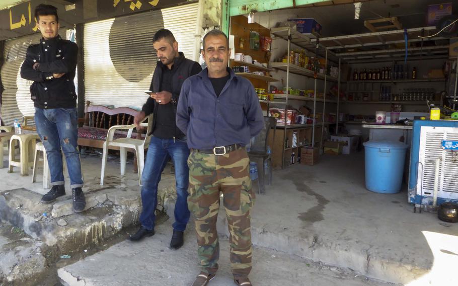 Bassam Makhmoud stands in front of a shop in Bahzani, Iraq, Monday, March 6, 2017. Makhmoud sells snacks, sodas and some tools, but the most popular item in this village, where life is returning after being liberated from the Islamic State group, is alcohol. The village was once known for producing the anis-flavored liquor called arak.