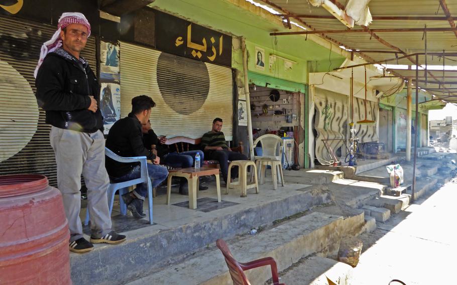Mulasm Ali stands in front of a shop where Bassam Makhmoud sells snack items, cigarettes and alcohol in the village of Bahzani, Monday March 6, 2017. The men say the village is safe, but they wonder about a future that they say could see a resurgent Islamic State group under a new name.