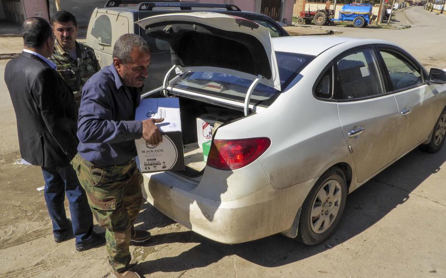 Bassam Makhmoud unloads a box of Black Jack whiskey from his brother's car in front of a shop where they sell alcohol and convenience items in the village of Bahzani, Monday, March 6, 2017. The village was liberated in November, and families and businesses have begun to return to the war-ravaged community after 2 1/2 years of Islamic State occupation.
