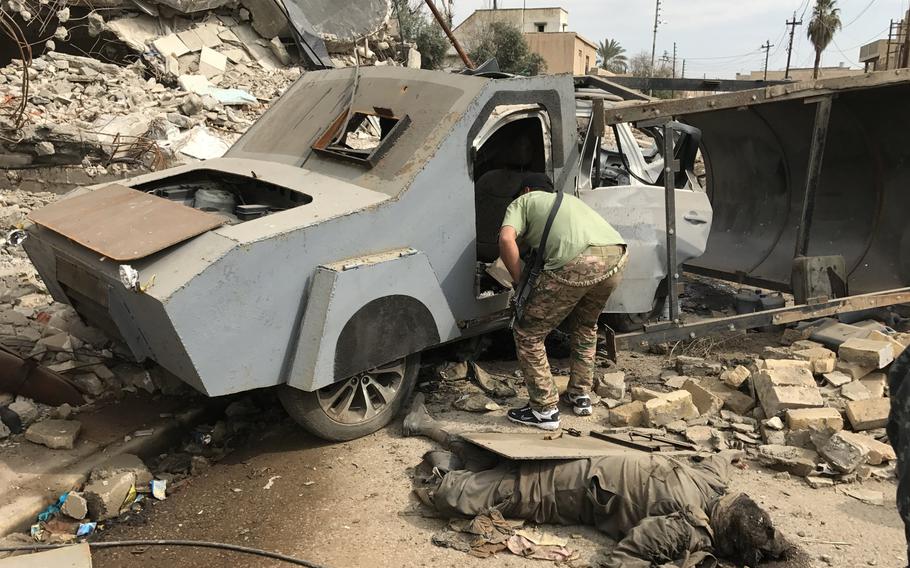 An Iraqi soldier peeks inside an up-armored car bomb on a street in a Mosul neighborhood on Wednesday, March 8, 2017. Iraqi forces stopped the suicide bomber, dead on the ground, before he had a chance to detonate his deadly SUV.