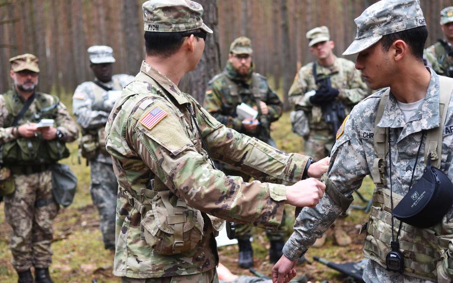 Instructors demonstrate how to tie a square knot to secure a patient to a stretcher during the Expert Field Medical Badge training at Grafenwoehr, Germany, Monday, March 20, 2017.