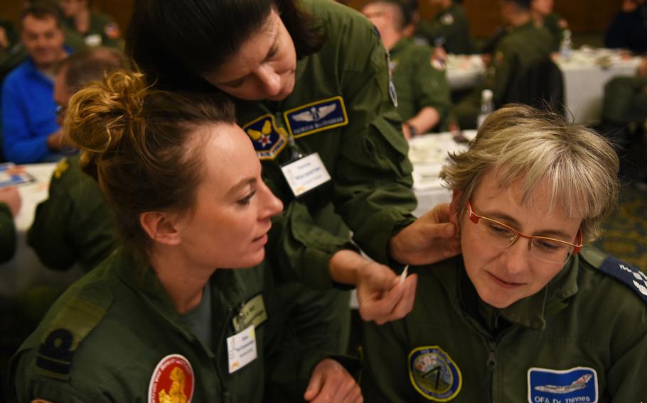U.S. Air Force Lt. Col. Patricia Macsparran, center, shows Capt. Tiel Groenestege, a flight surgeon in the Royal Netherlands Navy, where to place the needle inserter on the ear of Lt. Col. Katrin Thinnes, right, an anesthesiologist and ICU specialist with the German Air Force. Macsparran, the aerospace medicine consultant to the Air Force surgeon general, was one of the presenters Tuesday, March 21, 2017, at a workshop on battlefield acupuncture during an international aerospace medicine conference at Ramstein Air Base, Germany.