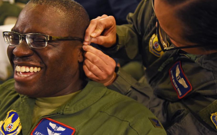 Col. Anthony Mitchell grimaces while Lt. Col. Stefanie Watkins-Nance inserts a needle into his ear during a battlefield acupuncture workshop on Tuesday, March, 21, 2017, at Ramstein Air Base, Germany.