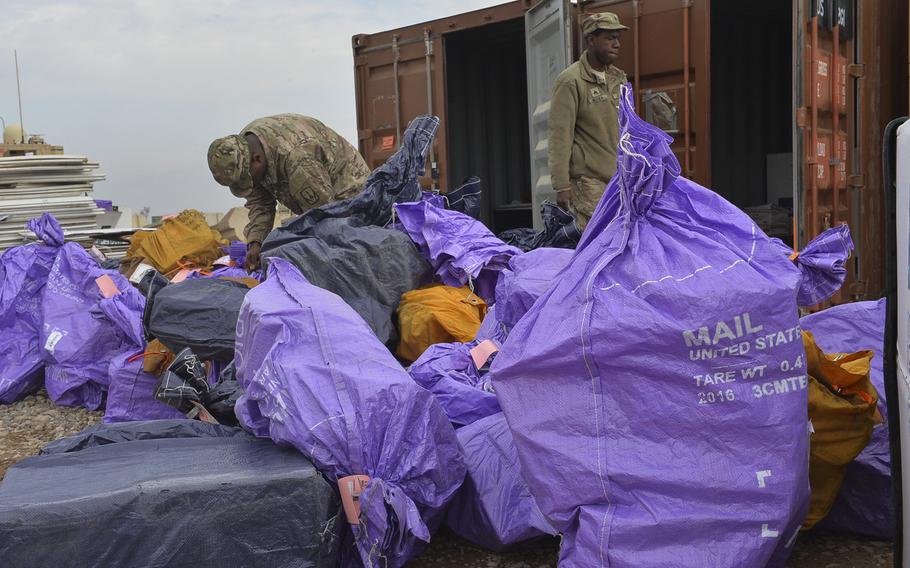 Sgt. Alvin Bethea Jr. walks past a pile of mailbags being sorted on Qayara Airfield West, March 17, 2017. Bethea, a soldier with the 678th Adjutant General Company Postal Platoon, said mail arrives about once every two weeks. Soldiers at the logistics hub about 40 miles south of Mosul say mail, especially care packages, is one of the few morale boosters here.