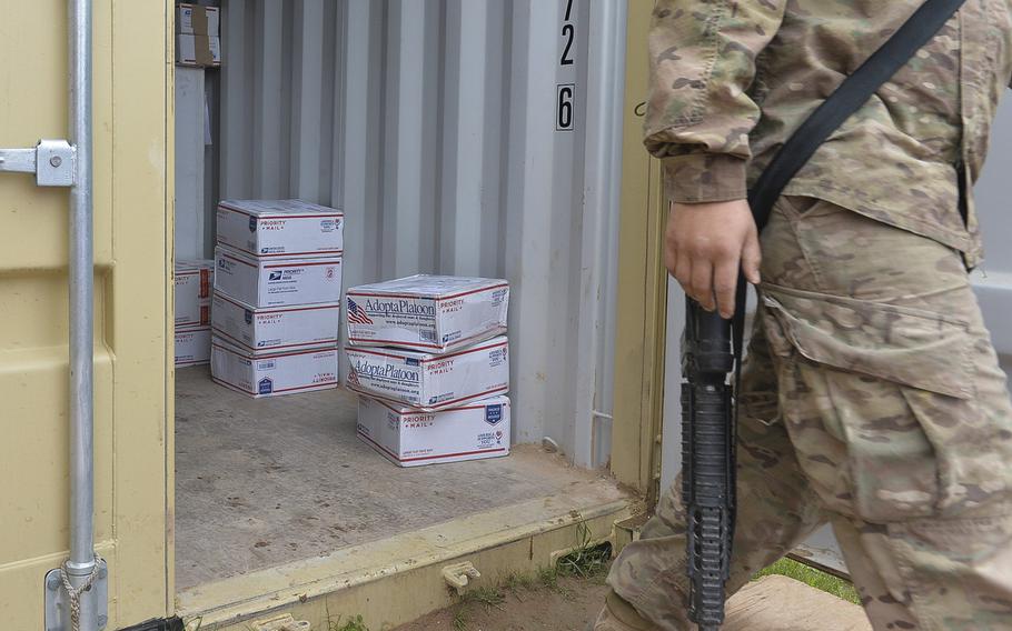 A soldier walks past stacks of care packages in a shipping container at Qayara Airfield West, Iraq, on March 17, 2017. Some of the packages, shipped through the nonprofit ''Adopt a Platoon,'' are sent by strangers in support of deployed troops who say they appreciate the small treats from home.