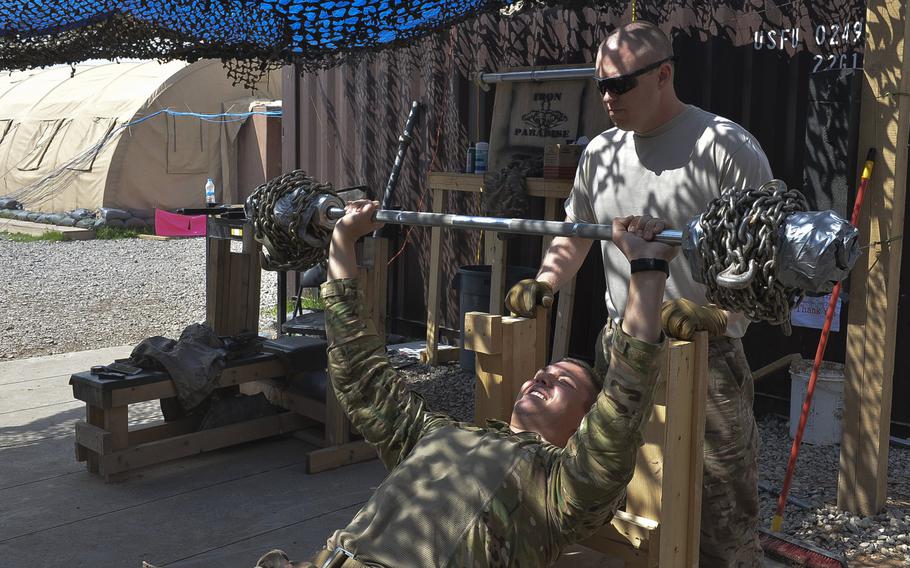 Senior Airman Troy Ondrey presses a makeshift barbell loaded with chains, about 135 pounds altogether, as Staff Sgt. Shawn Benton spots him in the 370th Air Expeditionary Advisory Group detachment's ''Iron Paradise'' gym on Qayara Airfield West, Iraq, March 17, 2017.