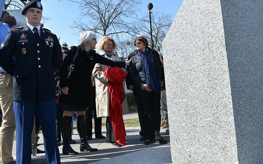 Helen Patton, left, reaches out to touch Luci Schey after they and Catherine Rommel, center, unveiled a monument marking the World War II crossing of the Rhine River by American troops in 1945 at Nierstein, Germany, Saturday, March 25, 2017. Patton is the granddaughter of Gen. George S. Patton while Rommel is the granddaughter of Erwin Rommel, the famous German general. Schey's foundation was  responsible for raising much of the money to build the monument.
