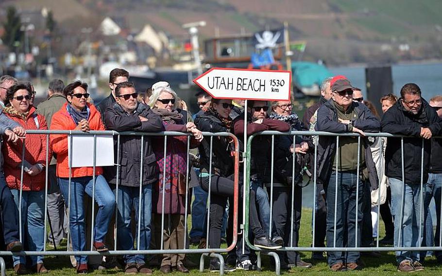 On the banks of the Rhine River, a sign points to Utah Beach, the D-Day landing beach, as people watch the unveiling ceremony of the dedication ceremony for the World War II Rhine River crossing monument in Nierstein, Germany, Saturday, March 25, 2017.
