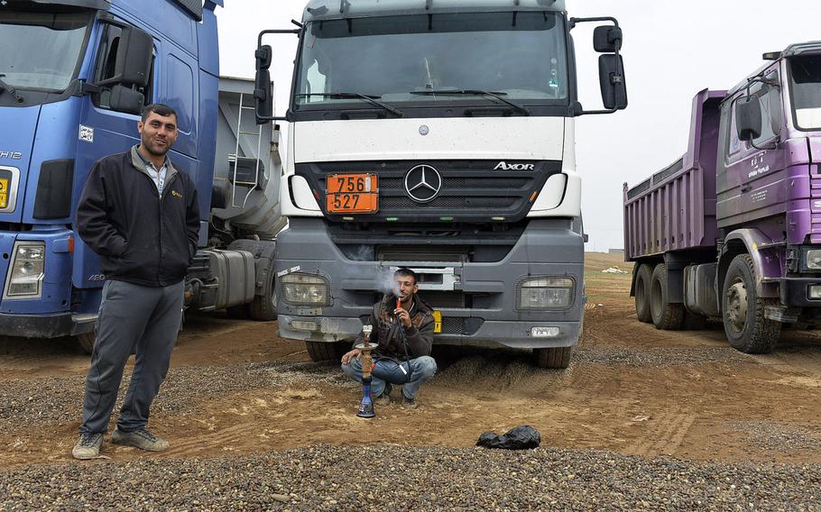 Iraqi drivers relax in front of their trucks, which brought tons of gravel to a coalition tactical base under construction south of Mosul, March 2, 2017.