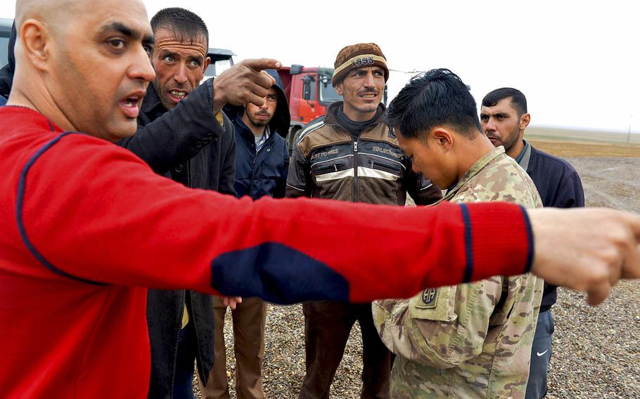 U.S. Army 1st  Lt. Adam Ward checks his notes as, left, Emaad Kudear, a contract linguist attached to the 2nd Battalion, 508th Infantry Regiment, passes on instructions to Iraqi truck drivers hauling gravel to a forward tactical base under construction south of Mosul, Iraq, March 2, 2017.
