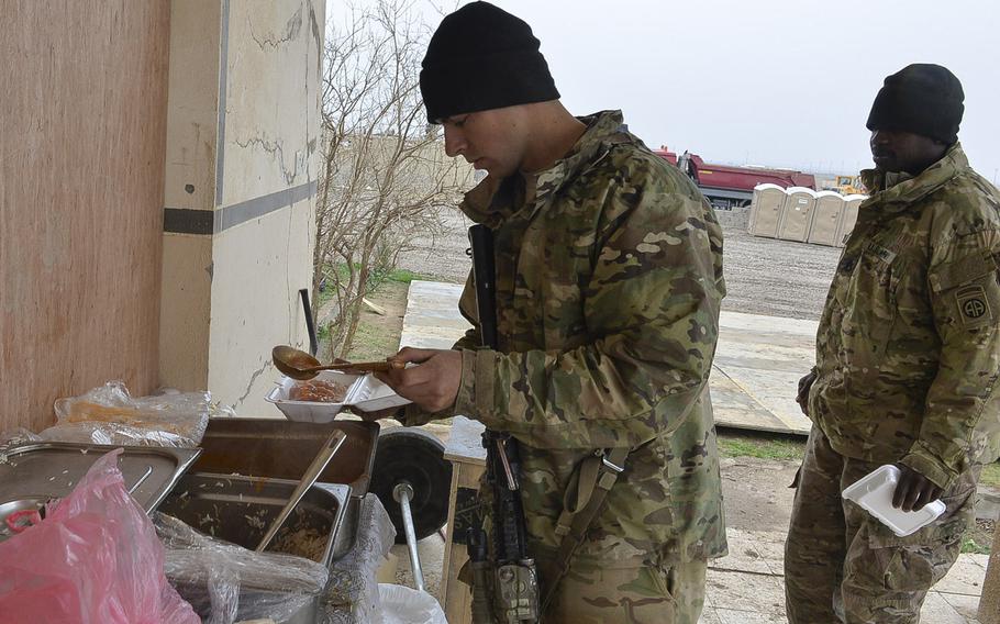 Spc. Humberto Cadena of Cookeville, Tenn., pours beans over his rice, part of a meal provided to U.S. advisers by the Iraqi army's 9th Amored Division, at a tactical base under construction south of Mosul, March 2, 2017.