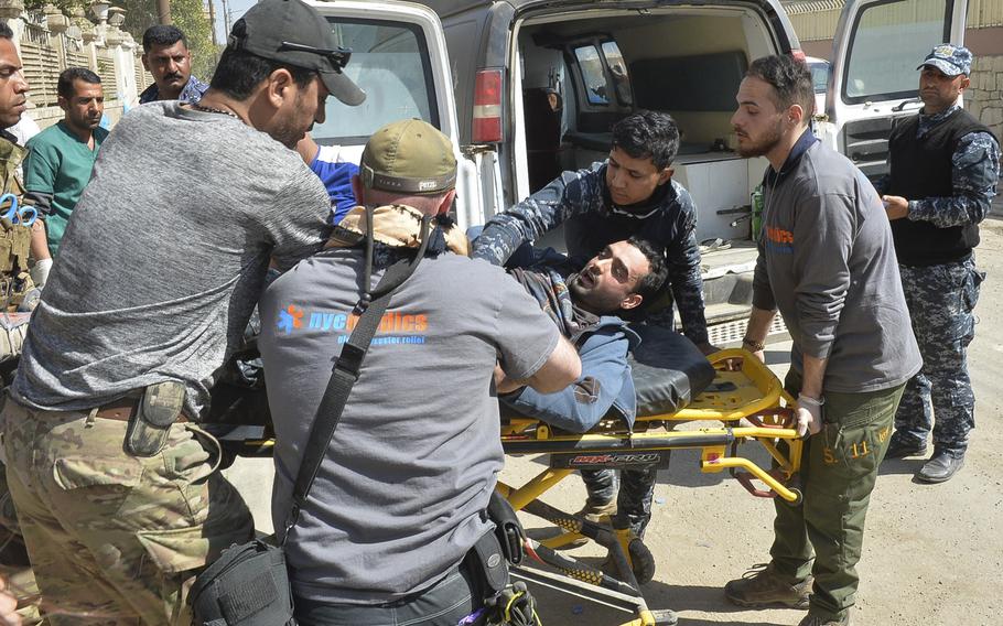 A wounded Iraqi federal police officer is carted to a medical station near the front lines of the battle for west Mosul, Iraq, March 9, 2017. Some of the attendants are volunteers with the New York-based organization NYC Medics, one of several groups partnered with the World Health Organization to help treat the casualties of the offensive in Mosul.