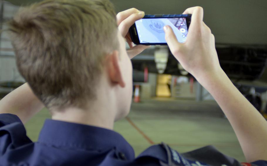 A Royal Air Force Air Cadet takes a photograph of a logo on an F-15E Strike Eagle during a tour of U.S. Air Force operations and equipment at RAF Lakenheath, England, Friday, April 7, 2017.