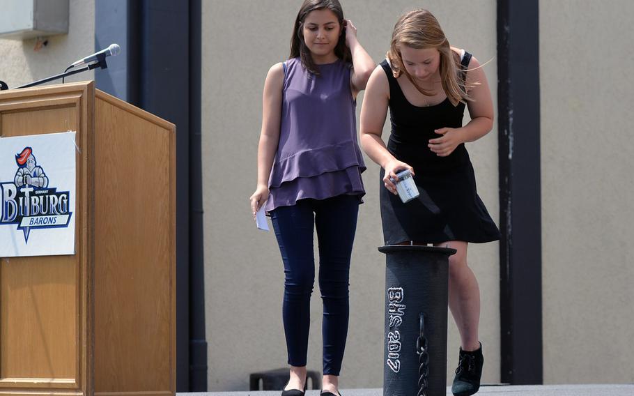 Chloe Karamzadeh, left, watches fellow senior Saige Caldwell place an item in a time capsule during Bitburg High School's closing ceremony, Thursday, June 8, 2017. Each class and the faculty put something in the capsule that is to be opened after 50 years.