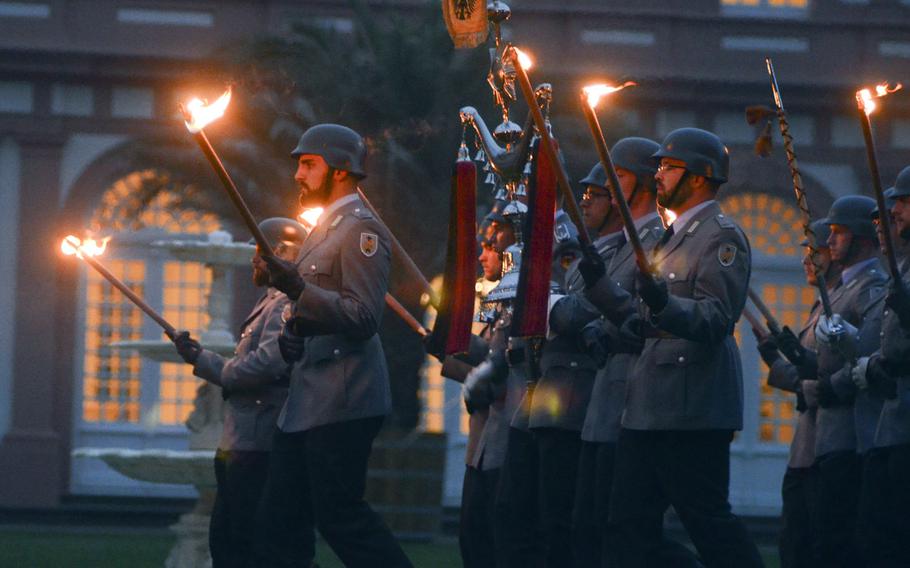 Bundeswehr soldiers carry torches as they march toward their positions at a Grosser Zapfenstreich, or Grand Tattoo, Thursday, Aug. 10, 2017 at Biebrich Palace in Wiesbaden, Germany.
