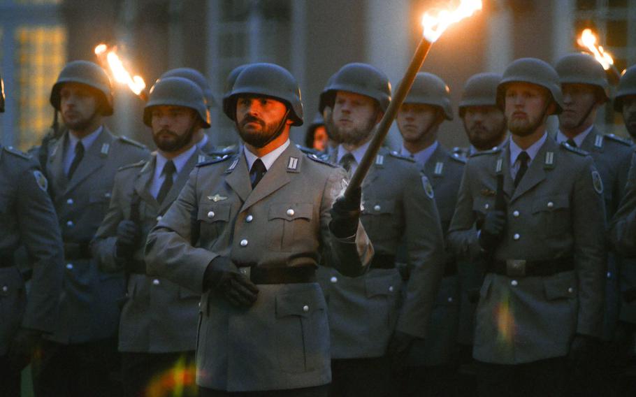 Bundeswehr soldiers carry torches as they march toward their positions at a Grosser Zapfenstreich, or Grand Tattoo, Thursday, Aug. 10 at Biebrich Palace in Wiesbaden, Germany.