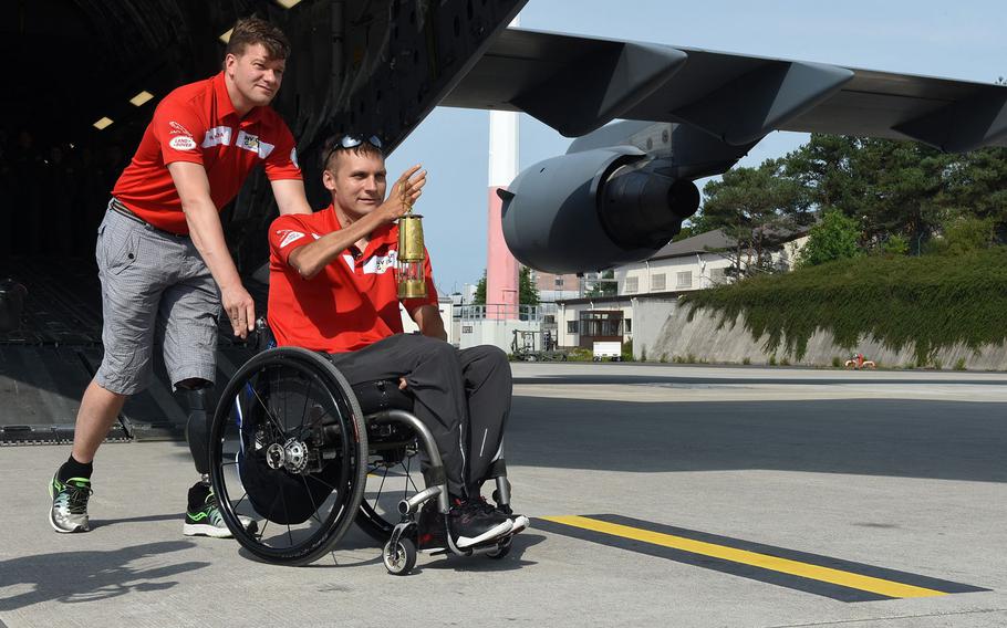 Simon Mailloux, a major with Canadian Forces, pushes Chris Klodt, a former Canadian Forces soldier on Tuesday, Aug. 15, 2017, at Ramstein Air Base, Germany. Klodt carried a lit lantern to symbolize the "spirit flame" for the upcoming Invictus Games next month in Toronto. Mailloux and Klodt were injured in Afghanistan.