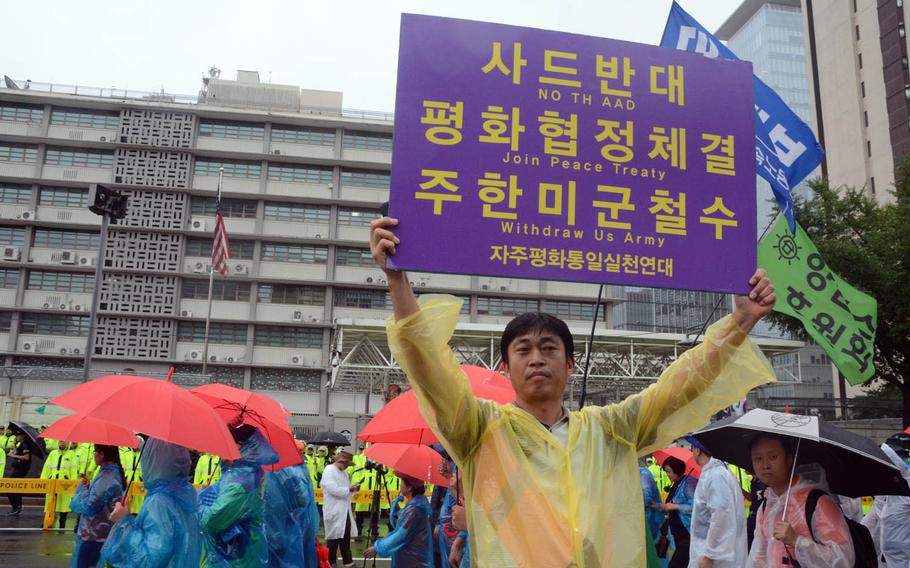 A man holds a sign during a South Korean protest in front of the U.S. Embassy in Seoul, Tuesday, Aug. 15, 2017. The sign called for the withdrawal of the U.S. Army, a peace treaty with North Korea and an end to the deployment of the advanced missile defense system known as THAAD.