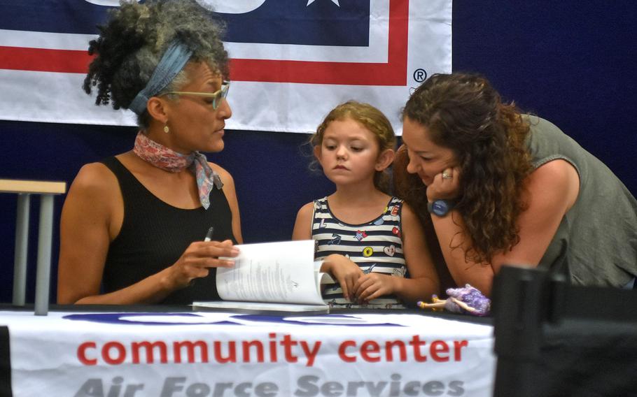 5-year-old Olivia Kirchhofer and mother Danielle watch celebrity chef Carla Hall sign a book on Wednesday, Aug. 23, 2017, at the base exchange. Hall is on a three-base USO tour in Europe before resuming her co-host duties on "The Chew' next week.