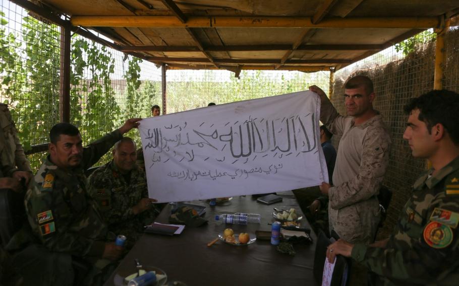 U.S. Marine Col. Matthew Grosz, right, senior advisor to Afghan army's 215th Corps, displays a captured Taliban flag during Operation Maiwand Five near Nawa district of Helmand Province, Afghanistan, Aug. 21, 2017. The flag holds significance as a sign of progress in clearing the Nawa district in Helmand province.