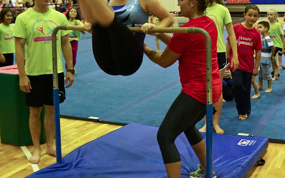 Desiree Sanchez, a 20-year veteran of USA Gymnastics who has previously worked alongside Olympic gold-medalists Shannon Miller and Dominique Moceanu, helps a gymnast spin on the bar during a youth gymnastics clinic at Yokota Air Base, Japan, Thursday, Aug. 30, 2017.