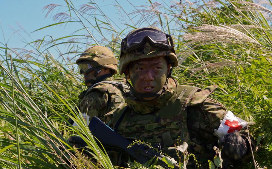 A medic with Japan's 34th Infantry Regiment, 1st Division, Eastern Army watches a medevac helicopter take off with a simulated casualty during Orient Shield drills at East Fuji Maneuver Area, Japan, Monday, Sept. 18, 2017.