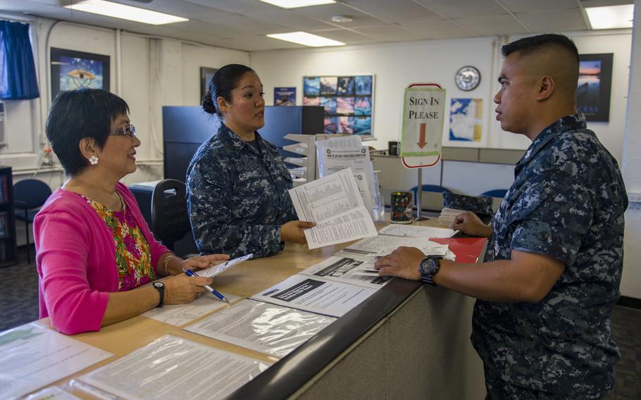 Gwyen Nosse, director of Navy College Office Hawaii, left, and Cryptologic Technician 2nd Class 'Gabriela Carrillo, explain the tuition assistance process to Culinary Specialist 1st Class Maximino Salvador at Joint Base Pearl Harbor-Hickam, Hawaii, Aug. 15, 2017.