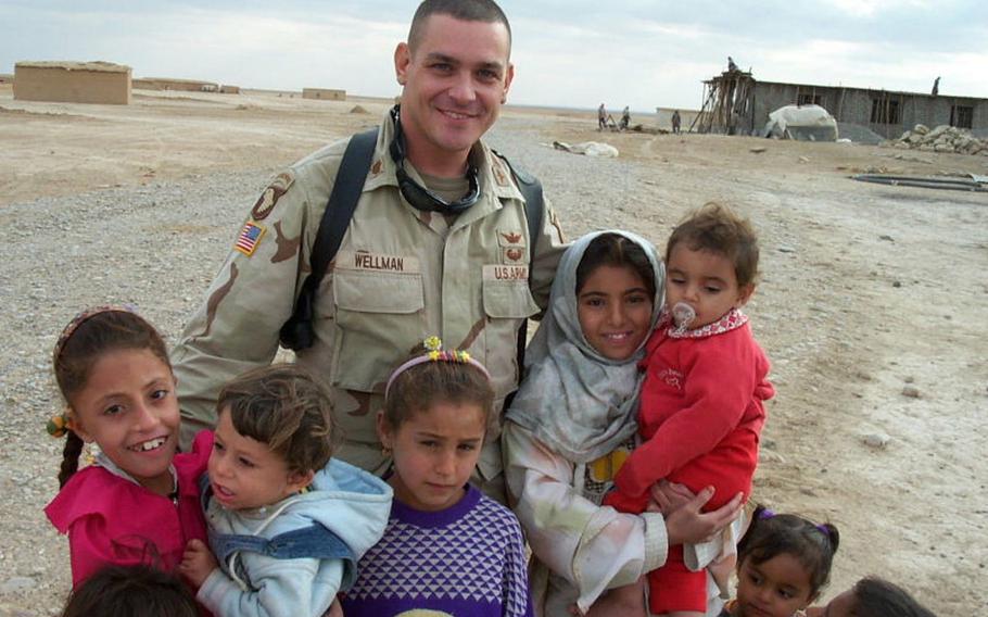 Pictured here on November 13, 2003, Fred Wellman, then a major in the U.S. Army's 101st Airborne Division combat aviation brigade, poses with the children of Jeddalah village near Qayara Airfield West, about 40 miles south of Mosul.
