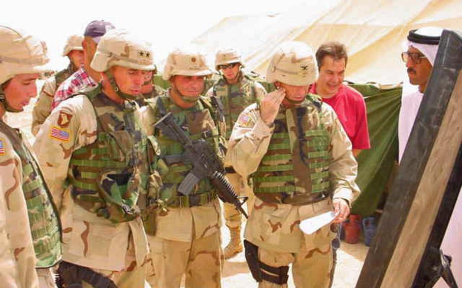 Then-Maj. Gen. David Petraeus is briefed by then-Maj. Fred Wellman, middle, and then-Col. Gregory Gass, right, on a visit to the village of Jeddalah on Thursday, July 10, 2003. Dr. Mohammed, the village sheikh and doctor, is in white on the far right.