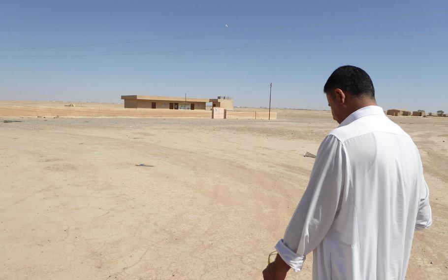 Hussein Ismail, sheikh of Jeddalah village near Qayara Airfield West, walks toward a school the Americans built in 2003, under the watchful eye of an American tethered aerostat at the base where U.S. troops have been supporting the Iraqi-led campaign against the Islamic State.