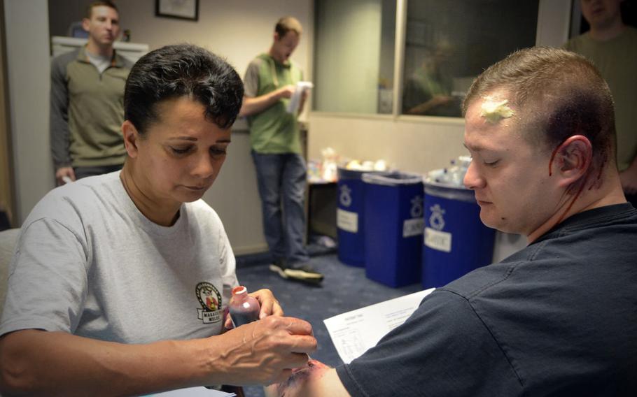 Karen Abeyasekere from the 100th Air Refueling Wing public affairs office applies a fake wound on U.S. Air Force Staff Sgt. David Davis before an active-shooter exercise at RAF Mildenhall, England, Wednesday, Oct. 18, 2017.