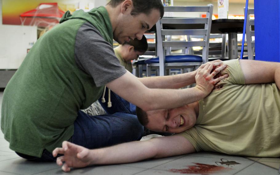 Airmen acting as simulated casualties try to stanch blood loss from gunshot wounds during an active-shooter exercise at RAF Mildenhall, England, Wednesday, Oct. 18, 2017.