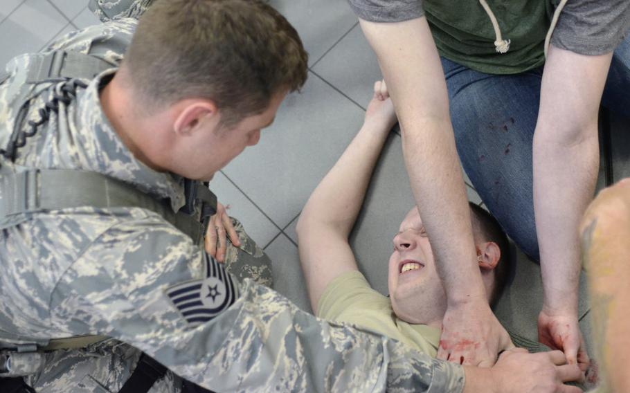 U.S. Air Force Tech. Sgt. Aaron Howard, 100th Security Forces Squadron, applies pressure to a gunshot wound on a simulated casualty during an active-shooter exercise at RAF Mildenhall, England, Wednesday, Oct. 18, 2017.