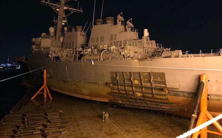 The collision-damaged USS John S. McCain is loaded onto a heavy-lift transport vessel in Singapore, Saturday, Oct. 7, 2017.