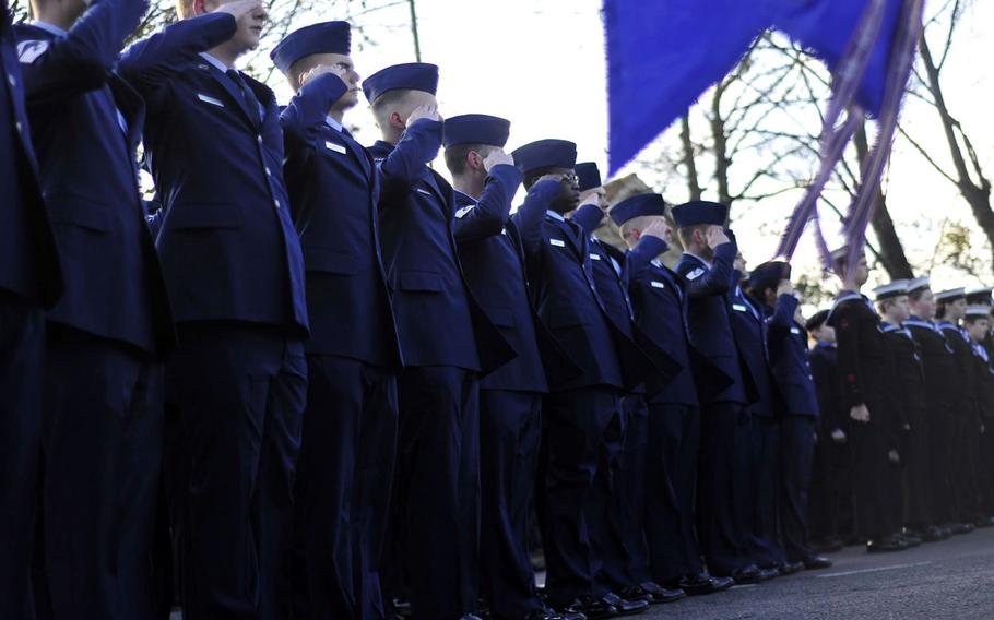 An airman first class, sixth from left, stands and salutes with others in formation during the playing of the British and American national anthems at a Remembrance Day ceremony in Mildenhall, England, on Sunday, Nov. 12, 2017. He later fell out and took a knee during reveille. Service officials said he was feeling faint, rather than protesting, following a flurry of angry comments on social media.