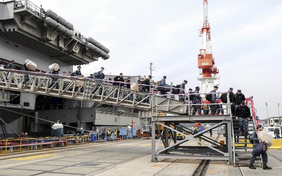 Sailors depart the aircraft carrier USS Ronald Reagan at Yokosuka Naval Base, Japan, Monday, Dec. 4, 2017.