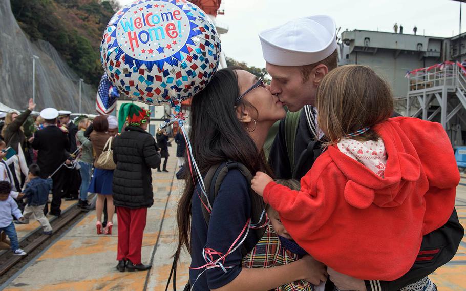Petty Officer 1st Class Reed Johnson of Davenport, Iowa, reunites with his family after the USS Ronald Reagan arrives at Yokosuka Naval Base, Japan, Monday, Dec. 4, 2017.