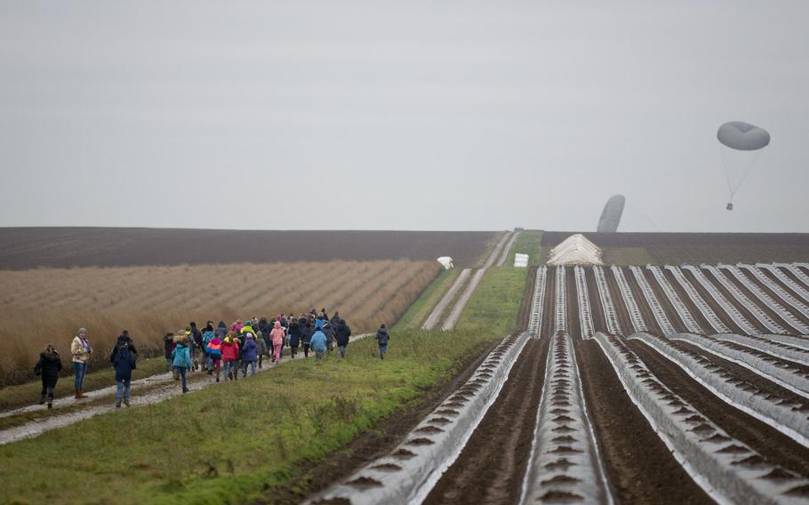 Children run toward a package dropped out of a C-130 near Alzey, Germany, on Wednesday, Dec. 6, 2017. About 100 paratroopers from the US, Germany and the Netherlands participated in a holiday training jump to give them experience jumping with personnel from other nations and to hand out toys to local children.